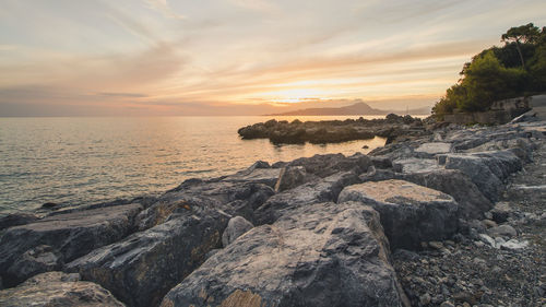 Rocks on beach against sky during sunset