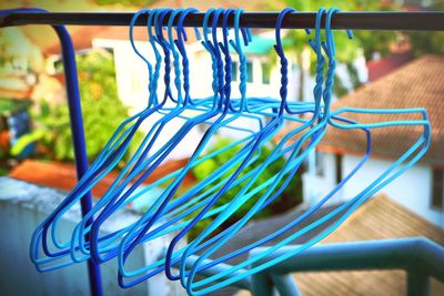 Close-up of blue coathangers hanging on rack in balcony