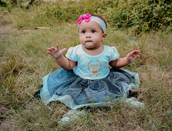 Cute baby girl sitting on land