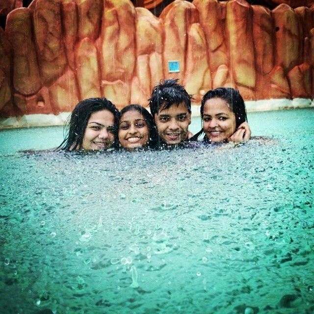 water, togetherness, lifestyles, leisure activity, bonding, reflection, waterfront, friendship, sea, love, front view, vacations, indoors, rock - object, standing, smiling