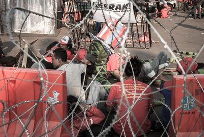 Protesters resting on road seen through fence in city