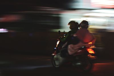 Blurred motion of people riding motorcycle on road