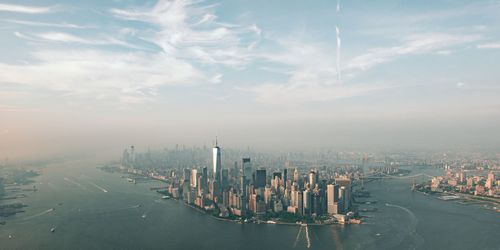 Aerial view of city buildings and sea against sky