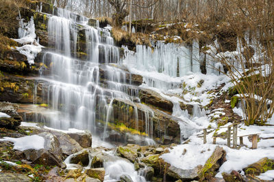 Scenic view of waterfall in forest during winter