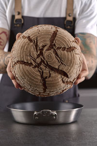 Hands holding rye sourdough bread over cooking pan