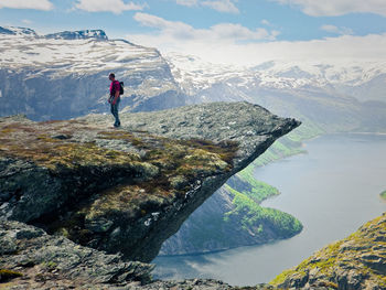 Man standing rocky cliff over lake