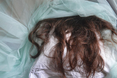 High angle view of human hair relaxing on bed