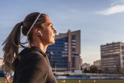 Portrait of young woman looking away against sky