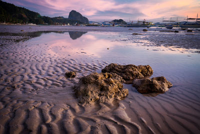 Rocks on beach against sky during sunset