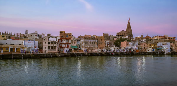 View of buildings by river against sky in town