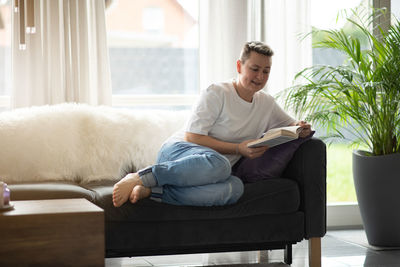 Young woman using laptop while sitting on sofa at home