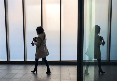 Full length of woman walking by window on floor