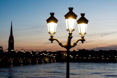 Illuminated street light in city at waterfront