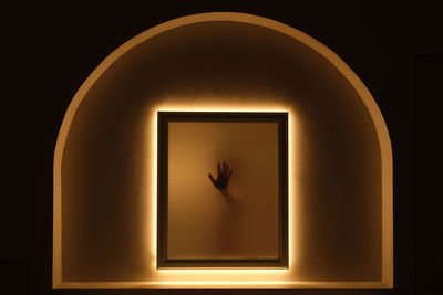 Silhouette of a hand against the light, behind glass