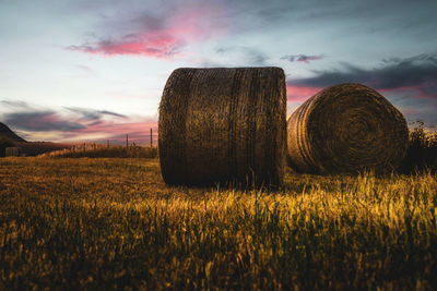 Hay bales on field against sky during sunset