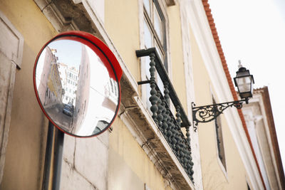 Low angle view of road mirror on building