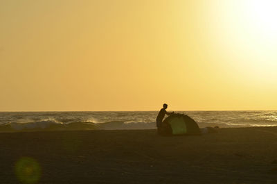 Men on beach against sky during sunset