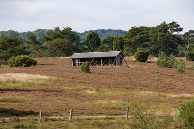 Gazebo on field by trees against sky