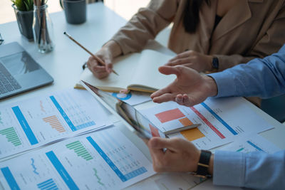 Midsection of business people working on table