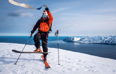 Man with umbrella on snowy mountain against sky