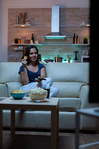 Young woman sitting on table at home