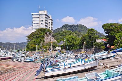 Boats moored at harbor by sea against sky