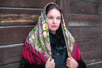 Smiling woman with blue eyes standing by wood