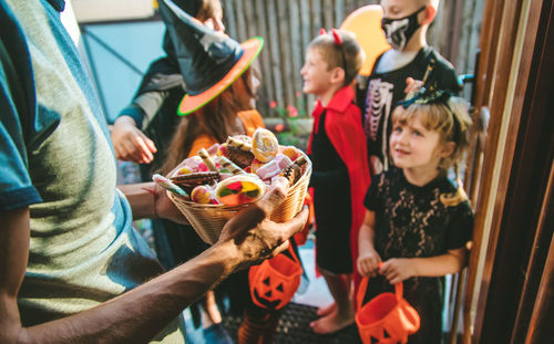 Man holding sweets in basket during halloween