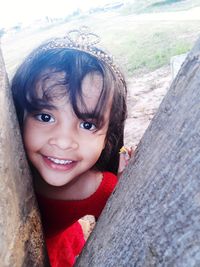 Portrait of cute girl standing by tree trunk