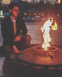 Midsection of man sitting on fire at night