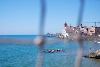 Sea with buildings against clear sky