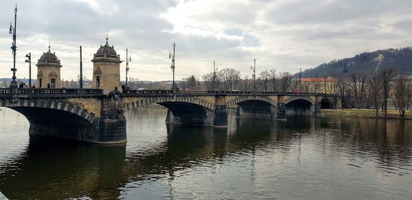 Arch bridge over river against cloudy sky