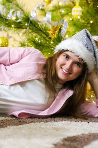 Portrait of smiling youth brunet woman 20-25 years wearing white santa hat and pink shirt. lying 