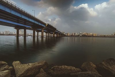 Bridge over river against cloudy sky