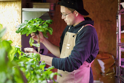 Chef wearing apron checking plant in restaurant garden