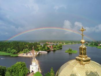 Scenic view of rainbow over river against cloudy sky