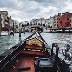 View of boats in canal against cloudy sky