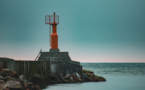 Lighthouse by sea against sky