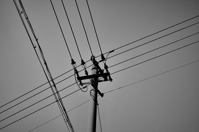 Low angle view of silhouette electricity pylon against sky