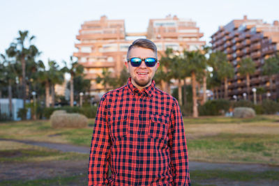 Portrait of young man wearing sunglasses while standing in city