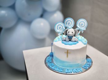 Close-up of candles and blue cristening baby cake on white table