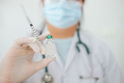 Midsection of doctor with syringe and vaccine