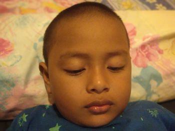 Close-up portrait of boy relaxing on bed