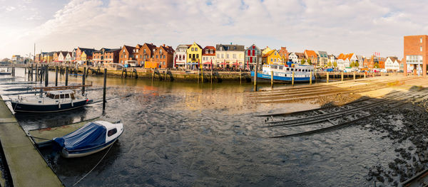 Boats moored in river against buildings at harbor