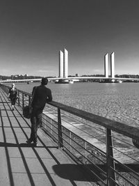 Rear view of man on bridge against clear sky