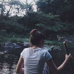 Rear view of woman on shore against trees