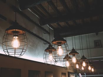 Low angle view of illuminated light bulb hanging from ceiling