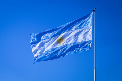 Low angle view of flag against blue sky