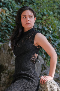 Portrait of young woman standing against plants