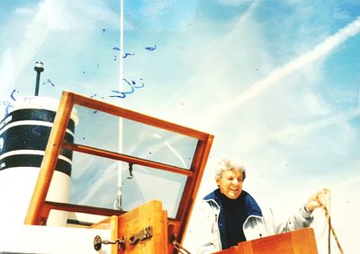 Happy man standing in ship against sky